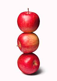A geometric arrangement of three red apples with harsh shadows on a white table.